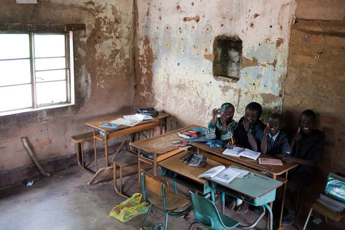 Meanwhile lessons continue in the farmhouse. Note how the desks have all been pushed into one area. This is due to the roof leaking during the rainy season. 
